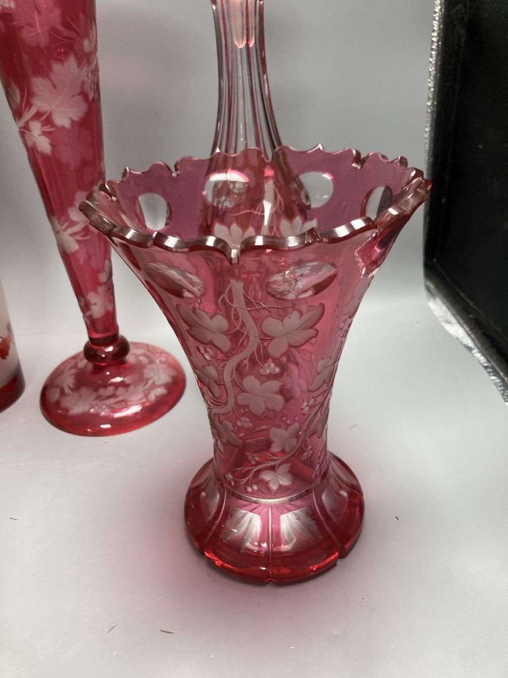 A collection of nine pieces of cranberry and ruby coloured glass, including a pair of decanters, two vases and a carafe and tumbler